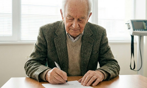 Older male nursing home patient signs an Advanced Beneficiary Form.